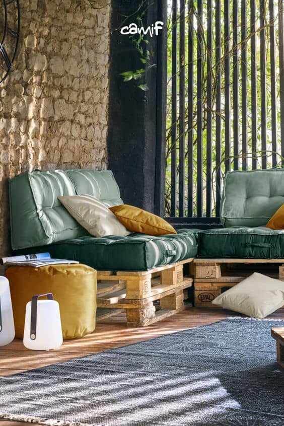 Un canapé en palette de bois et des coussins verts